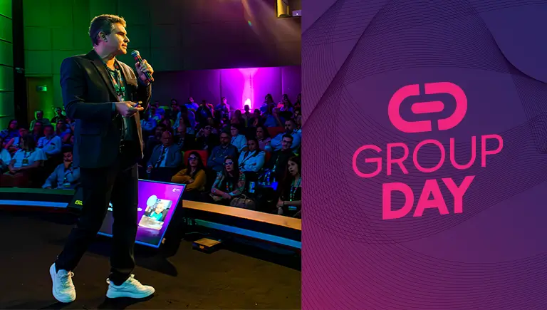 Rodrigo Monteiro, o CEO da Group Software, está no palco do Group Day, interagindo com o público em um ambiente iluminado com luzes coloridas.