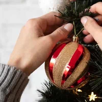 Uma pessoa decorando uma árvore de Natal em condomínios.