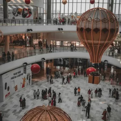 Shopping decorado com balões e caixas de presente, ilustrando ações promocionais e estratégias de marketing financiadas pelo Fundo de Promoção e Propaganda.